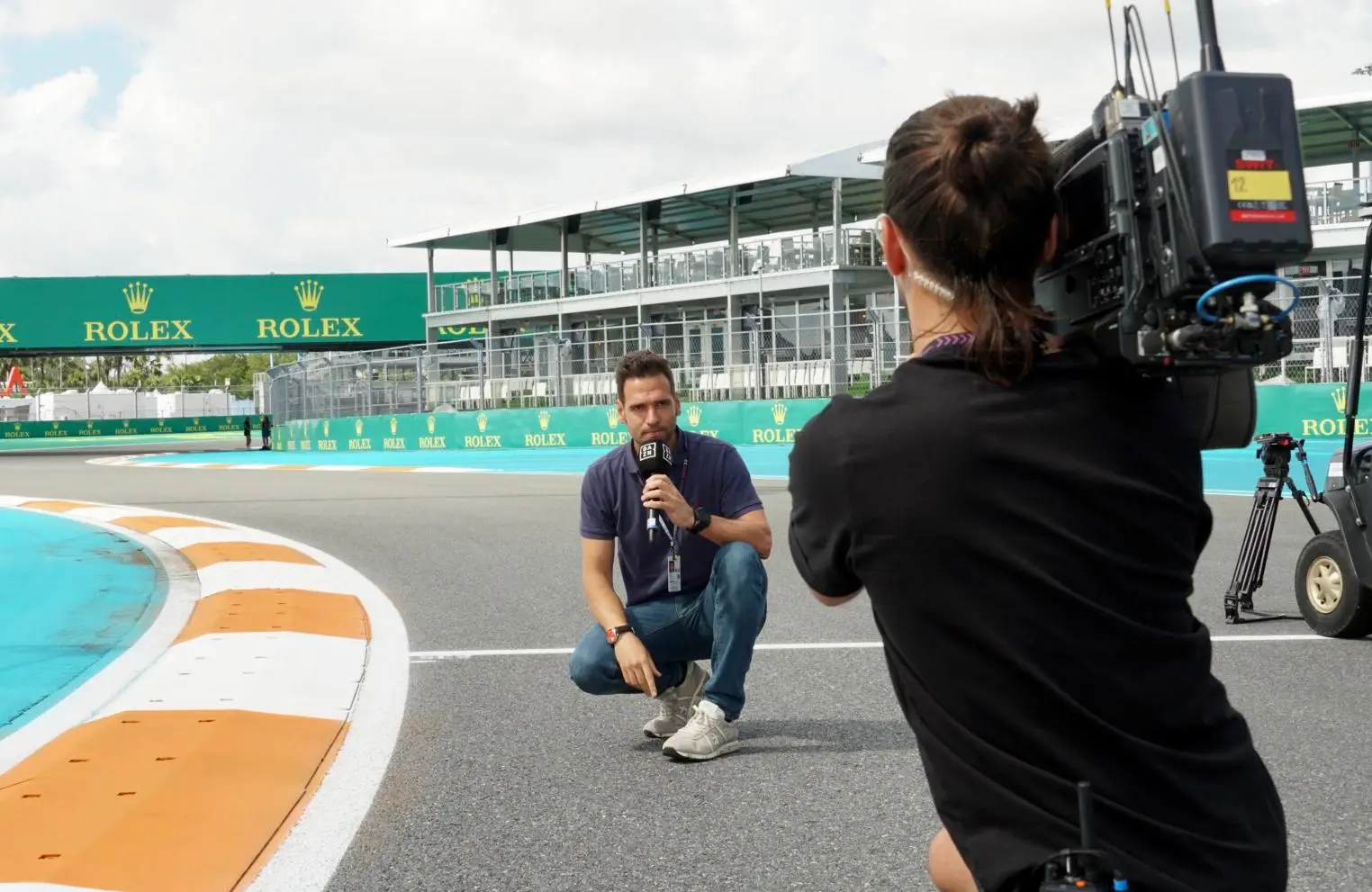 Roldán Rodríguez kneeling on track with a DAZN microphone at the Miami F1 Grand Prix